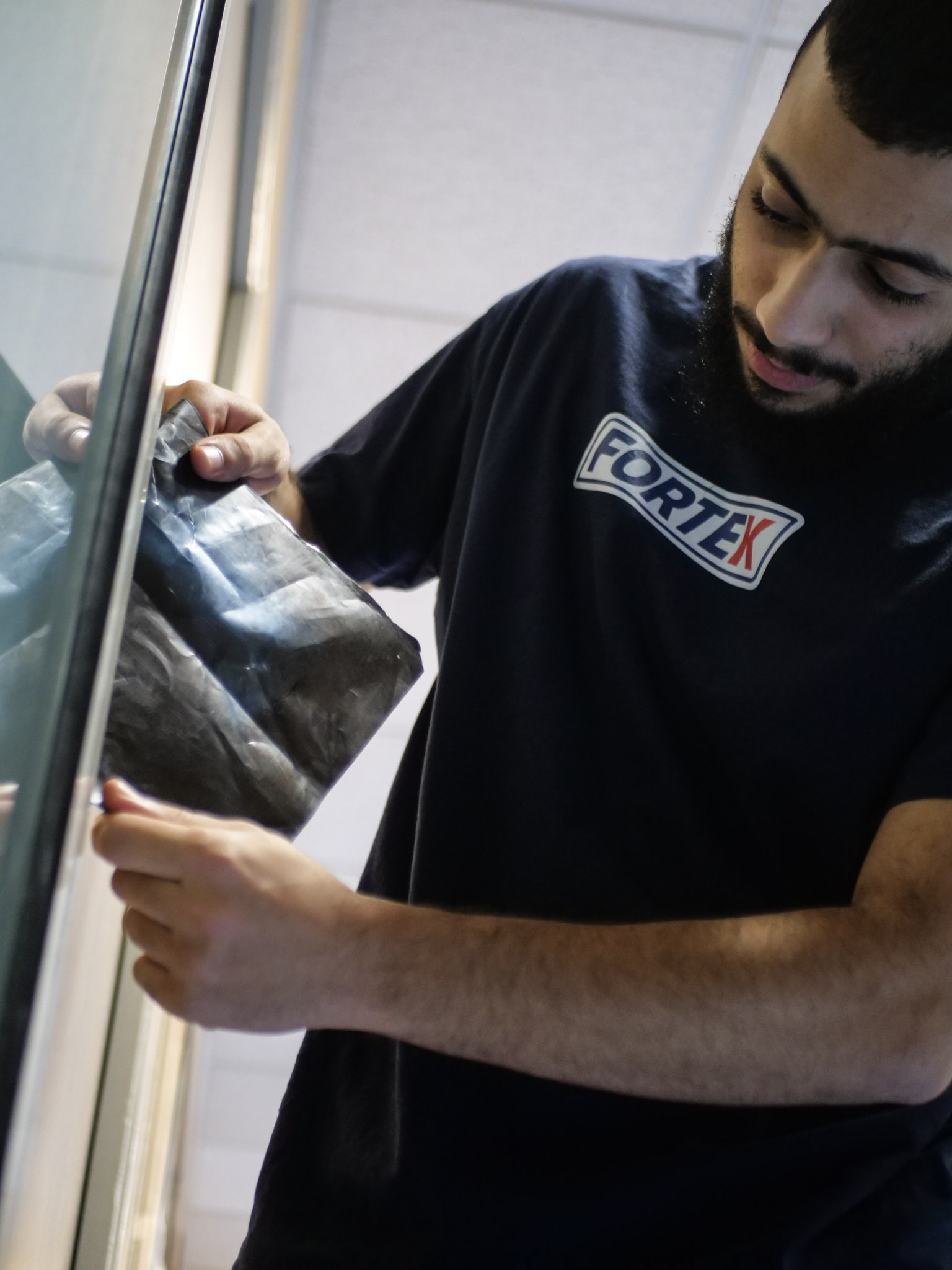 Technicien FORTEK avec radio et t-shirt bleu travaillant sur une ouverture de porte