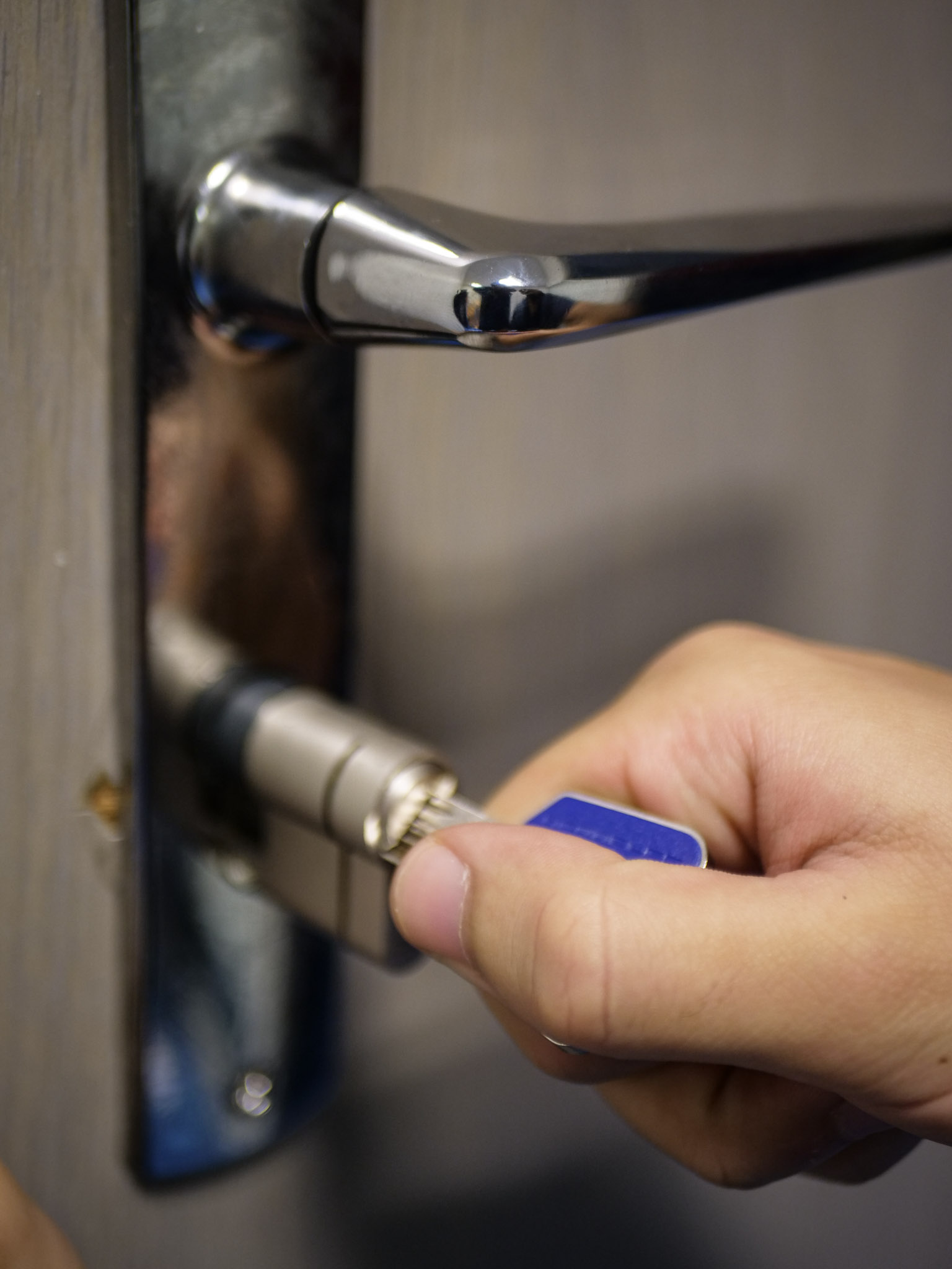 Main insérant une clé bleue dans un cylindre de serrure